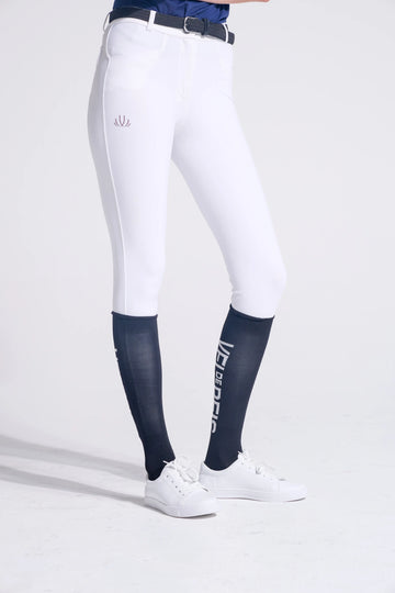 Rider wearing white breeches and VEL DE REIS navy compression show jumping socks with white sneakers