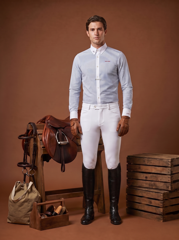 Male rider in full equestrian wardrobe standing beside a saddle, tack, and grooming kit