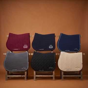 Set of six VEL DE REIS Equestrian saddle pads in various colors on a brown background