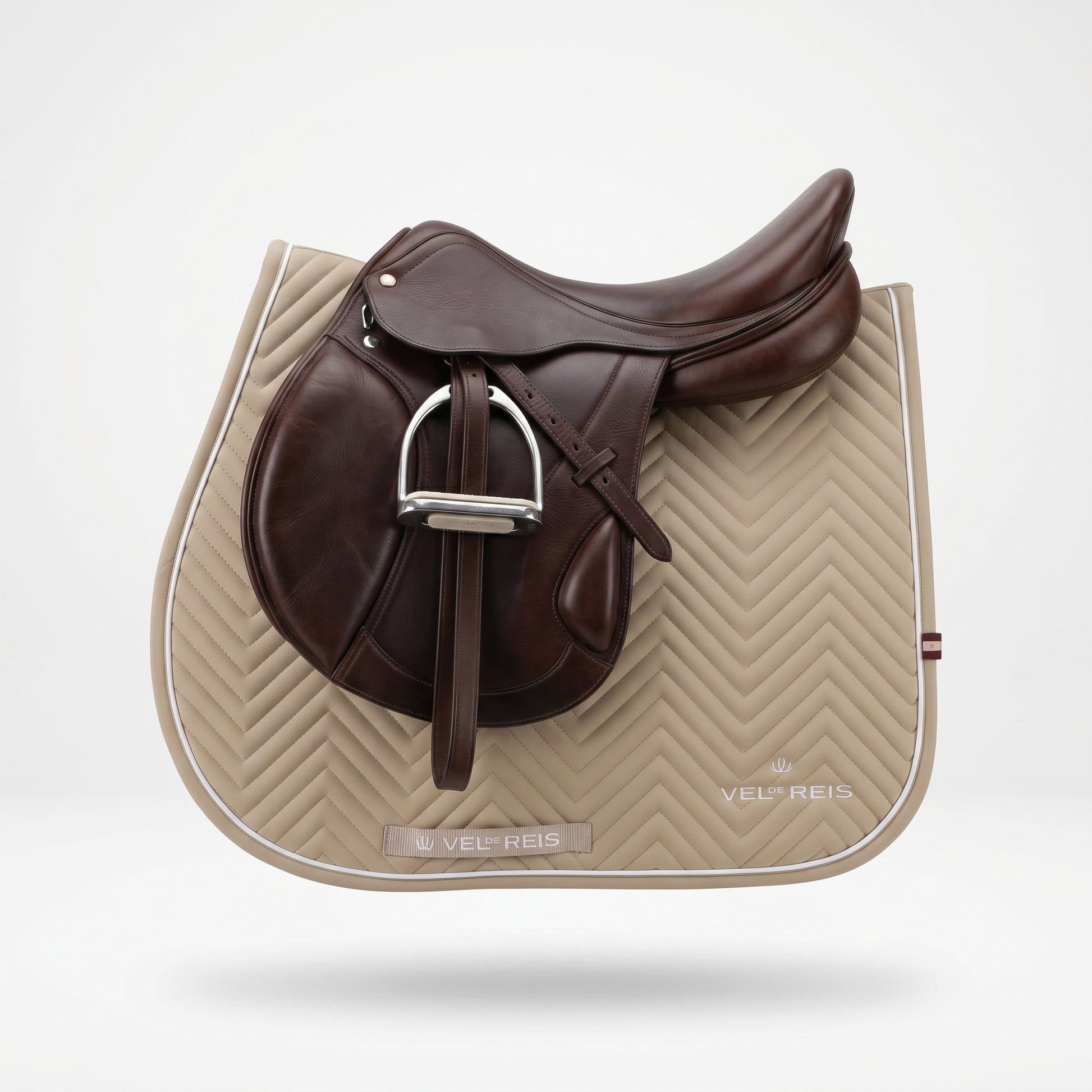 Brown saddle and VEL DE REIS beige quilted saddle pad on a white background