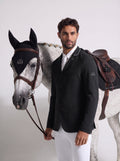 Man in equestrian attire standing next to a horse with a white background