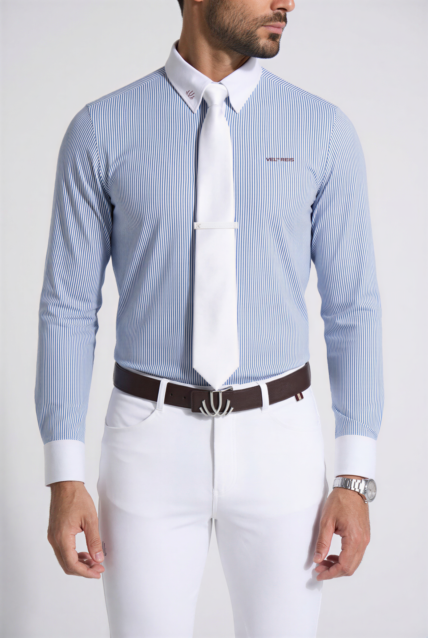 Man wearing a light blue striped dress shirt with a white collar and cuffs, paired with white pants on a plain background.
