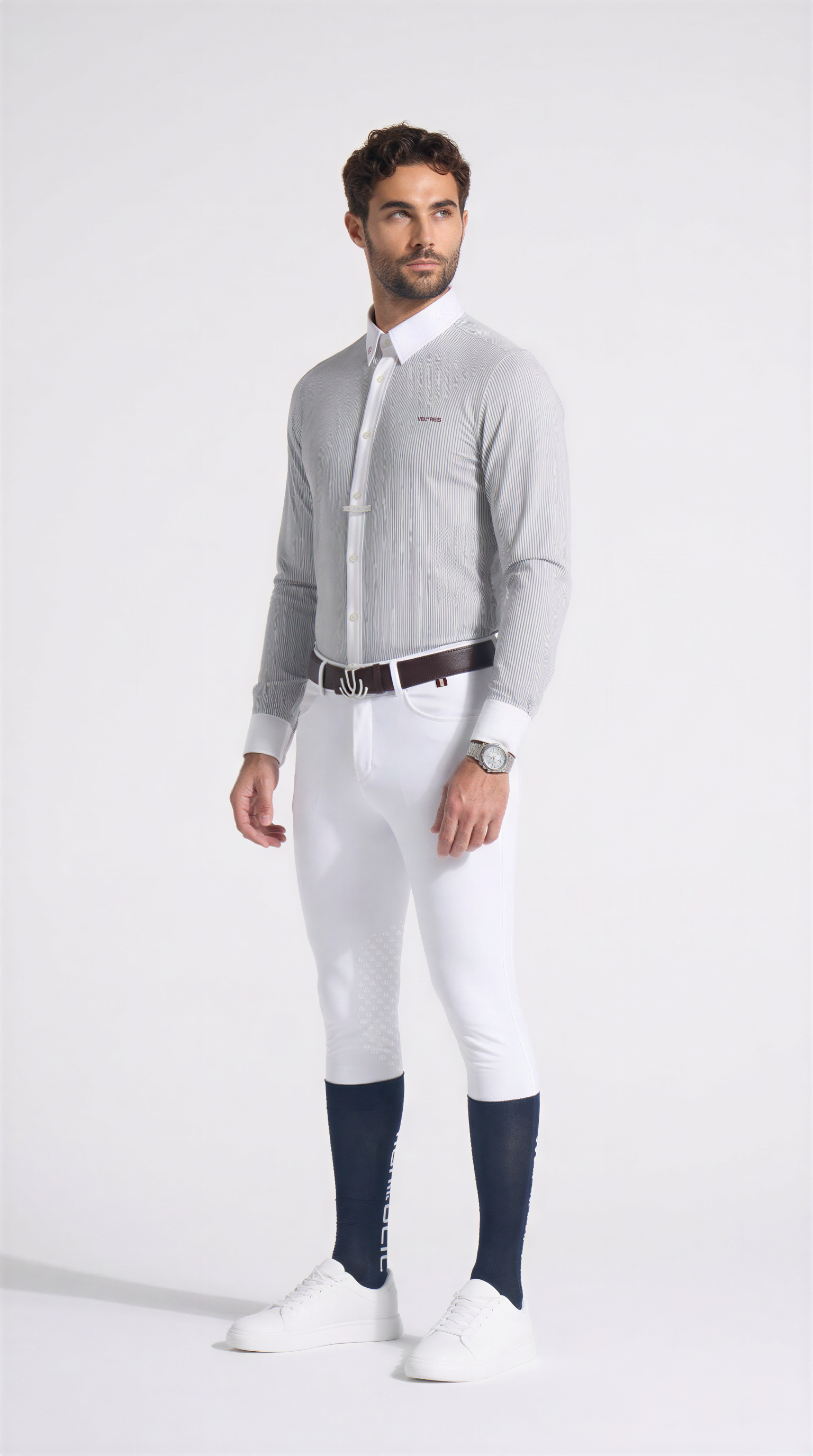 Man wearing a gray sweater, white pants, and navy socks on a white background