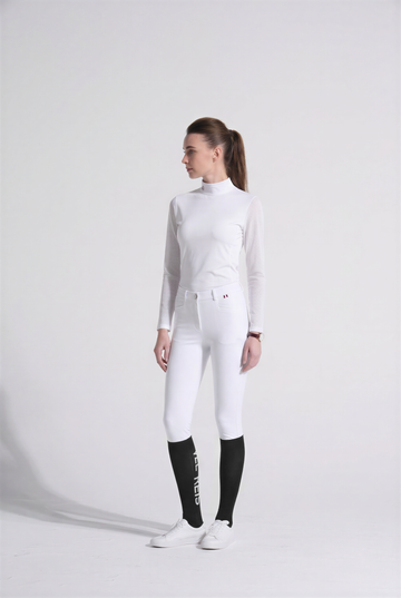 Person wearing a white VEL DE REIS equestrian outfit with black boots on a white background