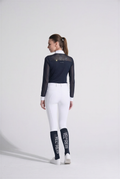 Person wearing a navy equestrian jacket and white pants with 'Kerrits' branding on a white background