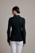 A woman shown from the back wearing a dark green fitted jacket with a subtle textured pattern on the back and white pants, set against a plain beige studio background.