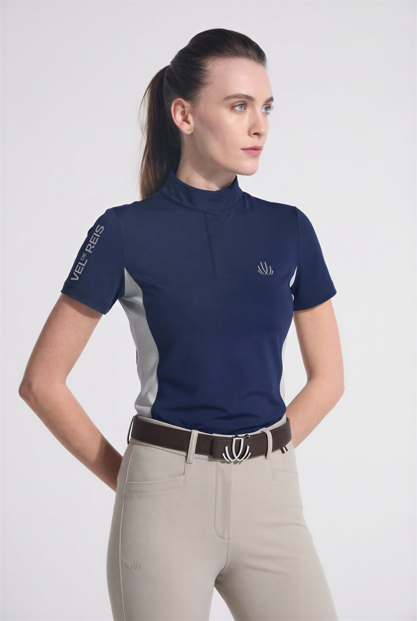 Woman wearing a navy equestrian Training shirt with a logo on a white background